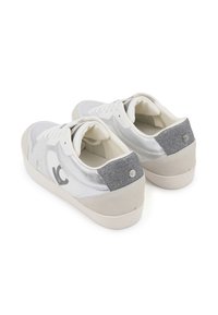 Zapatillas blancas con una combinación de materiales lisos y texturizados, acentos plateados y un panel trasero gris brillante.