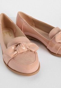 Ghete roz din balet, realizate din materiale din piele lăcuită și suede, cu un accent de fundiță răsucită în față și o talpă texturată din cauciuc.