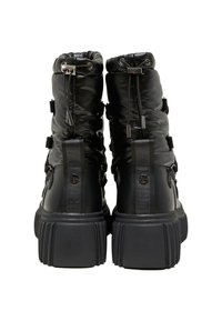 Černé vycpané boty s vysokým vrškem. Mají silnou podrážku, stahovací šňůrku a pásky po stranách. Lesklý povrch s raženým logem.