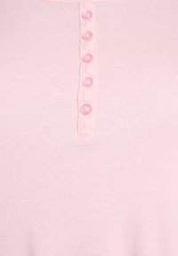 Šviesiai rožinė briaunota palaidinė su apvalia iškirpte, šešiais mygtukais su išlenktomis briaunomis ir glotnia, švelnia medžiagos tekstūra.