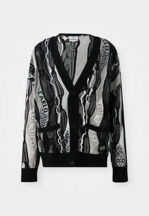 Knitted cardigan in black and white with a V-neck, buttons, two front pockets, and a geometric and text pattern. Texture appears lightweight.