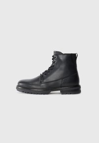 Black leather ankle boots with lace-up front, rounded toe, and rugged sole. Smooth texture with minimal stitching detail and pull tab.