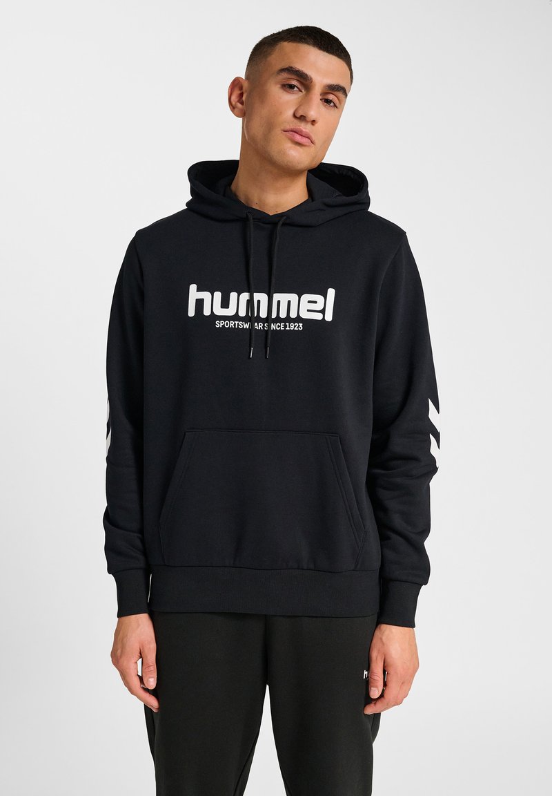 Svart hoodie i bomullsblandning med kenguruficka, dragskohuva och vit logotryck. Har vit chevronrand på ärmarna.