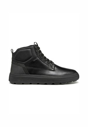Zapatillas altas negras de cuero suave, con detalles texturizados, punta redonda y suela de goma gruesa con dibujo circular.