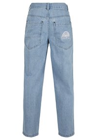 Lyseblå denim jeans med avslappet passform, med to baklommer og en hvit "SOUTHPOL"-logo over et regnbuegrafikk.