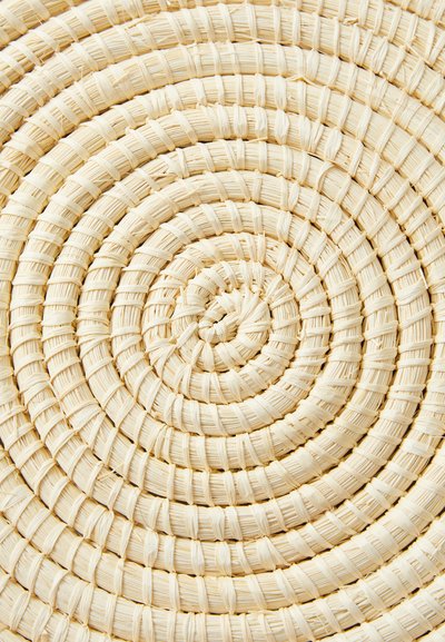 Round woven mat made of light beige natural fibers, featuring a spiral pattern with textured surface and neat stitching throughout.