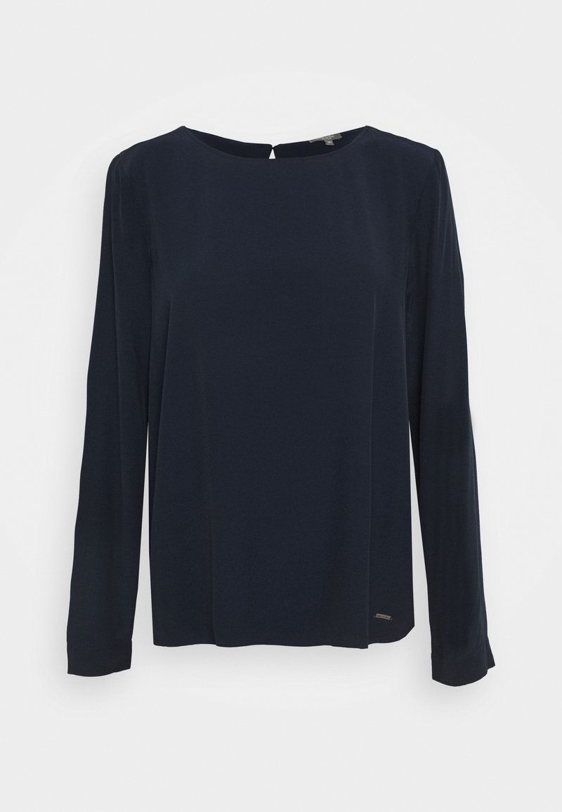 Blouse bleu marine à manches longues avec un col rond et une petite fermeture à bouton dans le dos, présentée sur un fond blanc uni.