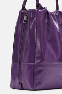 Sac à main en cuir violet vif avec une texture lisse et brillante, doté d'une fermeture à glissière et de poignées roulées. Marquage discret sur le côté.