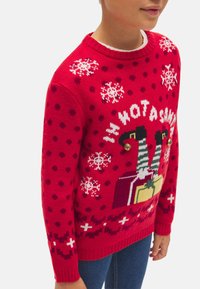Suéter rojo de punto que presenta copos de nieve, lunares y un diseño navideño con regalos. Puños y dobladillo acanalados. Llamativas campanas de jingles en el diseño.