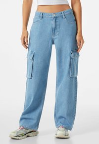 Ljusblå cargoj jeans av denim, med två stora sidofickor, en avslappnad passform och en knappstängning i midjan.