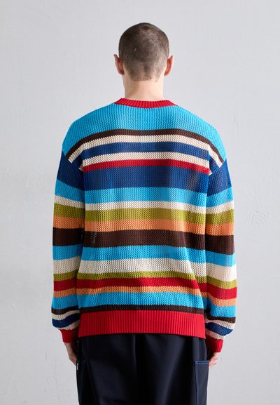 Pull en tricot à rayures multicolores, bleu, marron, rouge et vert. Présente un ourlet rouge côtelé et un tissu texturé. La vue arrière met en valeur le design.