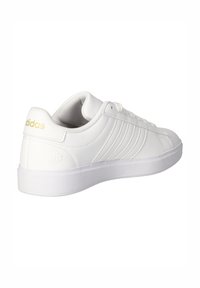 Hvid Adidas sneaker med guldlogo på hælen, tre hvide striber på siden og hvide snørebånd, set fra bagfra og i siden.