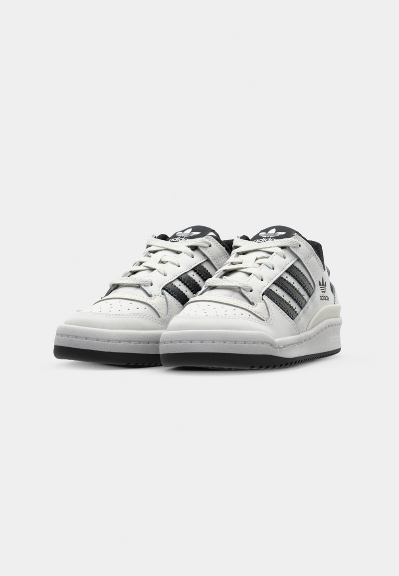 Witte leren sneakers met zwarte strepen en accenten, voorzien van een geperforeerde neus, ronde veters en een dikke rubberen zool.