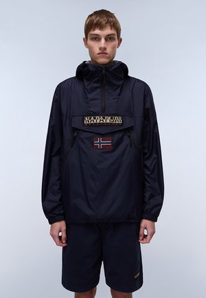 Mørkeblå vindjakke med hætte, der har en frontlomme og et norsk flag-patch. Materialet er glat og let.