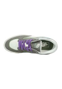 Zapatilla Vans con parte superior de ante gris y cuero blanco, que presenta cordones morados, puntera perforada y plantilla con marca. Suela de goma plana.