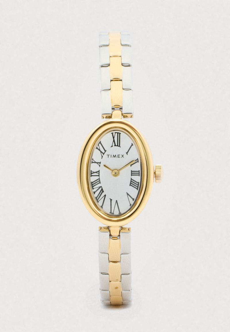 Oval Timex ur med guldfarvet bezel, hvid urskive, romerske tal og et tofarget armbånd i sølv og guld.