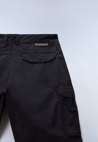 Die schwarzen Cargo-Hosen zeichnen sich durch einen strukturierten Stoff, mehrere Taschen, ein Taillenbandetikett und einen geraden Schnitt mit sauberem Abschluss aus.