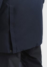 Marine waterdichte jas met een gladde textuur, voorzien van een zijsplit, drukknoopsluiting en een stijlvolle, recht gesneden ontwerp.