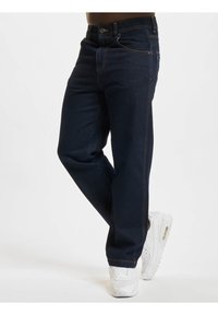 Temno modri jeans z oranžnimi šivi, klasična zasnova s petimi žepi, ravna kroja in gumbom za zapiranje v pasu.