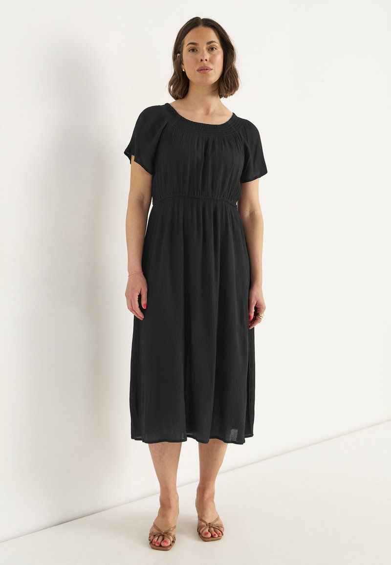 Schwarzes Midi-Kleid mit kurzen Puffärmeln, gerafftem Ausschnitt und taillierten Bund. Leichter, strukturierten Stoff fließt bis zum Knöchel.