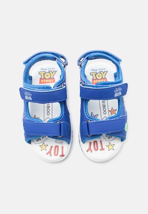 Niebieskie dziecięce sandały z logo Toy Story oraz wkładką z motywem postaci, gwiazdkami i napisem, regulowane paski z zapięciami na rzep.