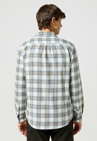 Geruite flanellen overhemd in lichtblauw, bruin en roomkleurig. Lange mouwen, knopenmanchetten, rugpanddetail, gebogen zoom. Zachte textuur.