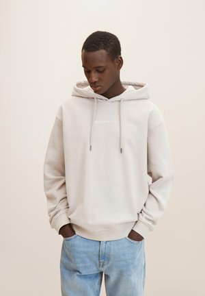 Light gray hoodie with a drawstring, featuring "DENIM" in white print. Paired with light blue jeans, showing a relaxed fit and simple design.