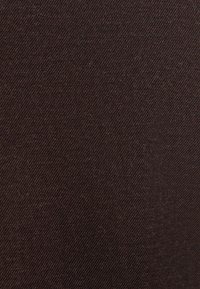 Tessuto marrone che mostra un motivo a trama diagonale, con una superficie leggermente texture e fibre fini visibili in tutto il materiale.