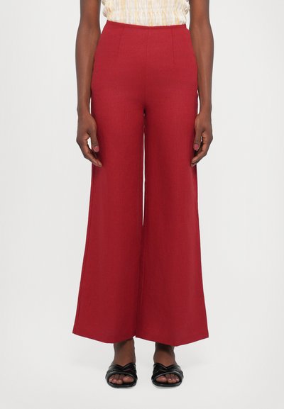 Red, wide-leg trousers made of textured fabric with a high waist. Features clean lines with no visible fastenings or pockets.