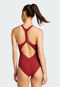 Red one-piece swimsuit featuring a racerback design with a cut-out detail. Made from smooth fabric with sleek lines and a form-fitting shape.