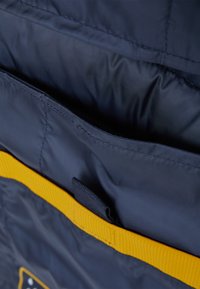 Marineblaue Stofftasche mit einem gelben Akzentband, das über eine glatte Textur verfügt und einen kleinen schwarzen Schlaufenhalter zur Befestigung hat.