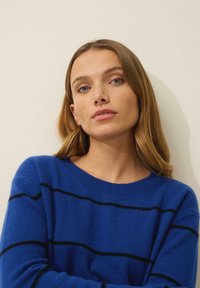 Blårandig tröja i mjukt material med horisontella svarta ränder, rund halsringning och långa ärmar. Slät textur.