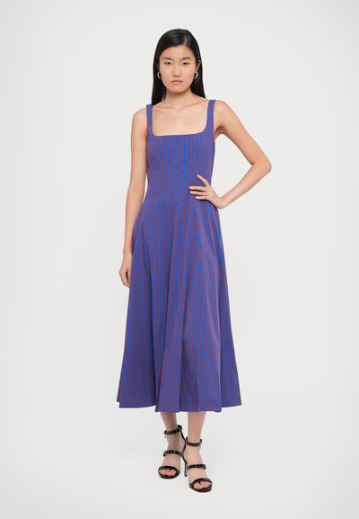 Blue and red striped dress with a square neckline, fitted bodice, and flared skirt. Model wearing black strappy sandals.