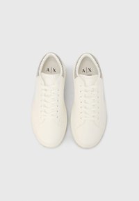 Λευκά αθλητικά παπούτσια με λείο δερμάτινο επάνω μέρος, στρογγυλή μύτη και υφασμάτινες λεπτομέρειες στη φτέρνα. Διαθέτουν επίπεδα κορδόνια και λογότυπο στη σόλα εσωτερικά.