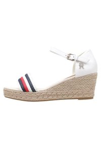 Sandalo bianco a zeppa con suola in juta intrecciata, caratterizzato da accenti a righe blu navy e rosse sulle cinghie. Cinturino alla caviglia regolabile con fibbia metallica.