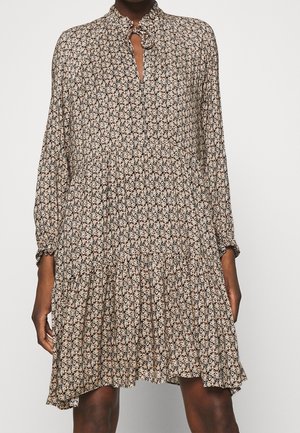 Long-sleeve, floral patterned dress with a keyhole neckline and ruffled cuffs, falling above the knees on a dark-skinned model.