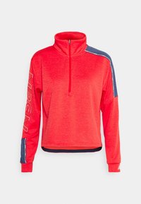Pullover rosso in pile a mezza zip con maniche lunghe, dettagli blu navy sulle spalle e testo bianco del marchio sulla manica sinistra. Texture liscia, vestibilità rilassata.