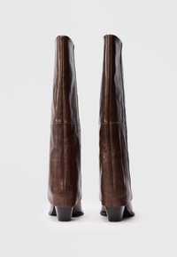Braune Lederstiefel in knöchelhoher Ausführung mit eng anliegendem Design. Glatte Oberfläche, taillierte Form und niedrige Blockabsätze. Keine sichtbaren Verschlüsse oder Verzierungen.