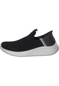 Sneaker nera senza lacci con tomaia in maglia testurizzata, accento sul tallone grigio a contrasto e suola in gomma bianca con motivo rigato.