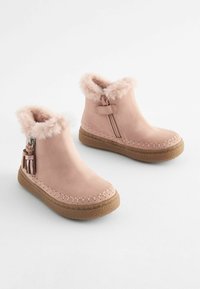 Roze suede enkellaarsjes met nepbont trim, een zijrits en decoratieve franje. Voorzien van een rubberen zool met textuur voor grip.