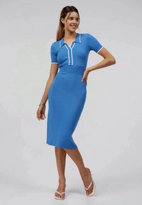 Ribbad, ljusblå klänning med korta ärmar och krage. Har vitt kantband och en figursydd midi-silhuett.