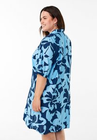 Helles blaues Kleid mit einem dunkelblauen Blumenmuster, kurzen Ärmeln, Knopfdetails, leichtem Stoff und einer lockeren Passform.