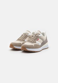 Sneaker beige e marroni con una tomaia in suede e tessuto, punta rotonda, design con lacci, dettagli bianchi e suola in gomma.