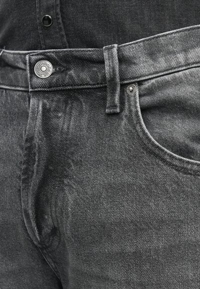 Jeans in denim nero con una texture liscia, dotati di chiusura a bottone, passanti per cintura e una leggera sfumatura sul tessuto. Tasca anteriore visibile.