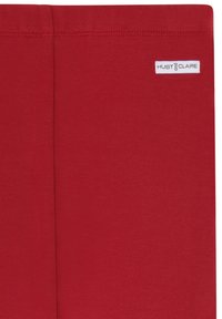 Roter Baumwollstoff mit glatter Textur, der in der Mitte eine Naht aufweist und ein kleines weißes Etikett mit der Aufschrift "HUST und CLAIRE" trägt.