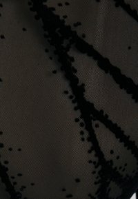 Czarna koronka o półprzezroczystej jakości. Posiada wzór kropek i teksturowanych pasków, tworząc warstwowy efekt.