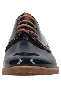 Chaussure habillée en cuir verni noir avec des lacets marron et une semelle marron clair, vue de face sur un fond blanc.