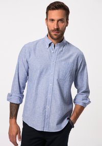 Hellblaues Hemd mit Knöpfen, einer Brusttasche, hochgerollten Ärmeln und einem subtilen, strukturierten Muster. Hergestellt aus einem weichen, gewebten Stoff.