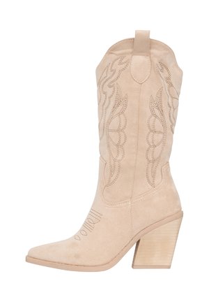 Bota cowboy de ante beige con punta afilada y patrones de costura curvados. Presenta un tacón de madera gruesa y texturizada, y lengüetas para facilitar su uso.