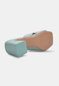 Aqua blue platform heel with a square shape, glossy texture, and light tan rubber sole. Features a sleek design and smooth finish.